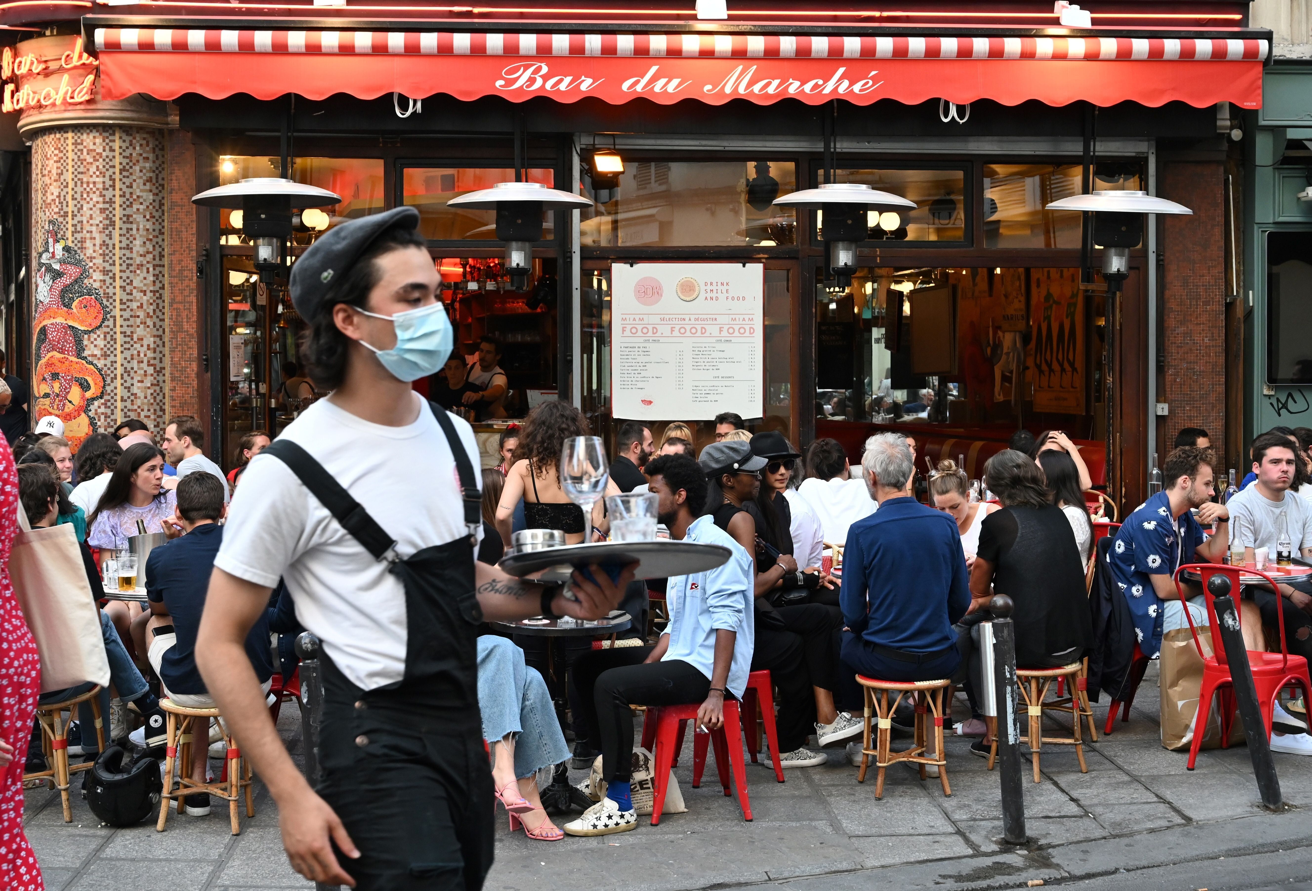 Un serveur avec un masque devant la terrasse du Bar du marché, le 2 juin 2020 (Photo by BERTRAND...