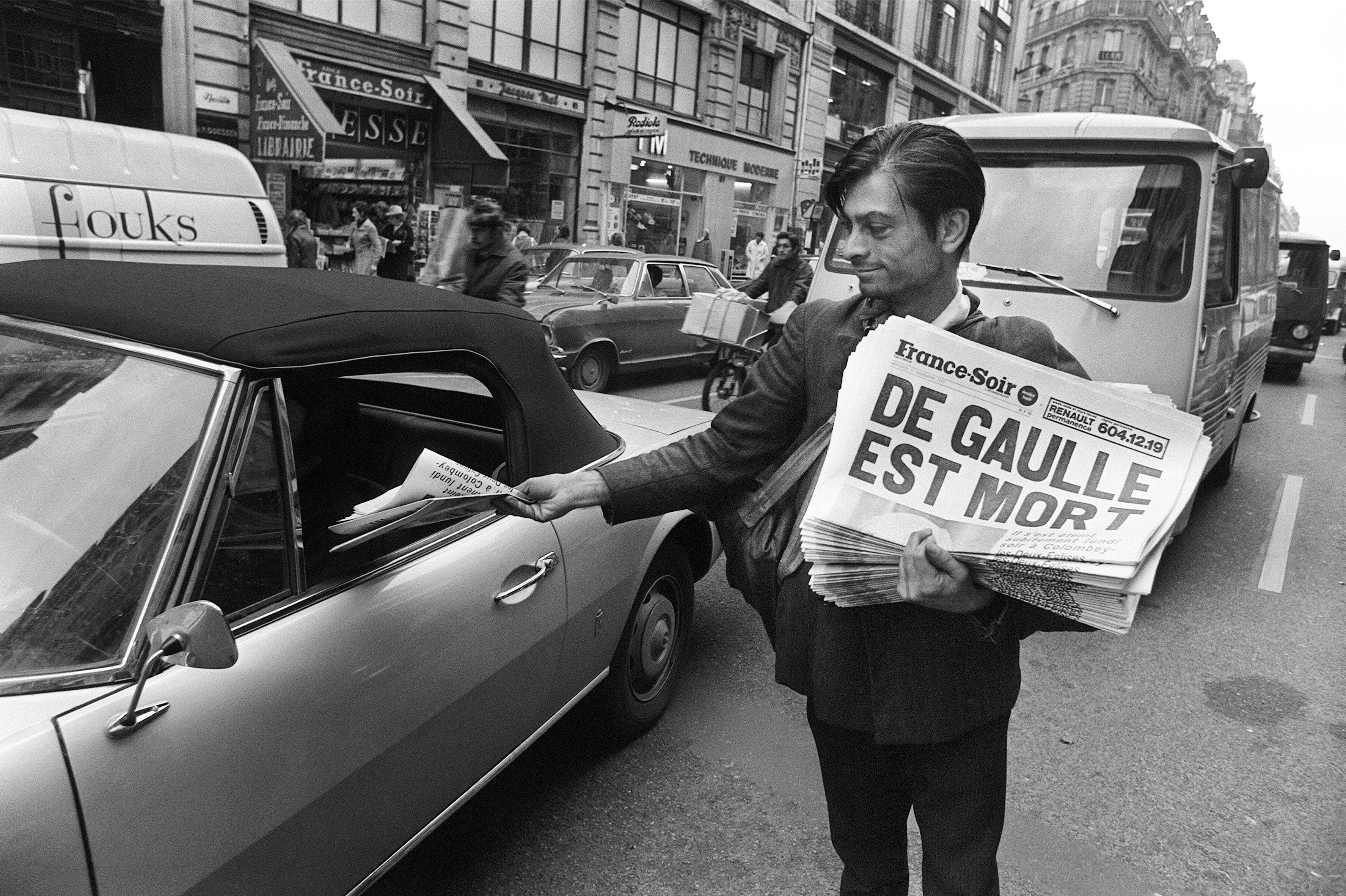 Un vendeur de rue propose à un automobiliste le journal France-Soir annonçant la mort du...