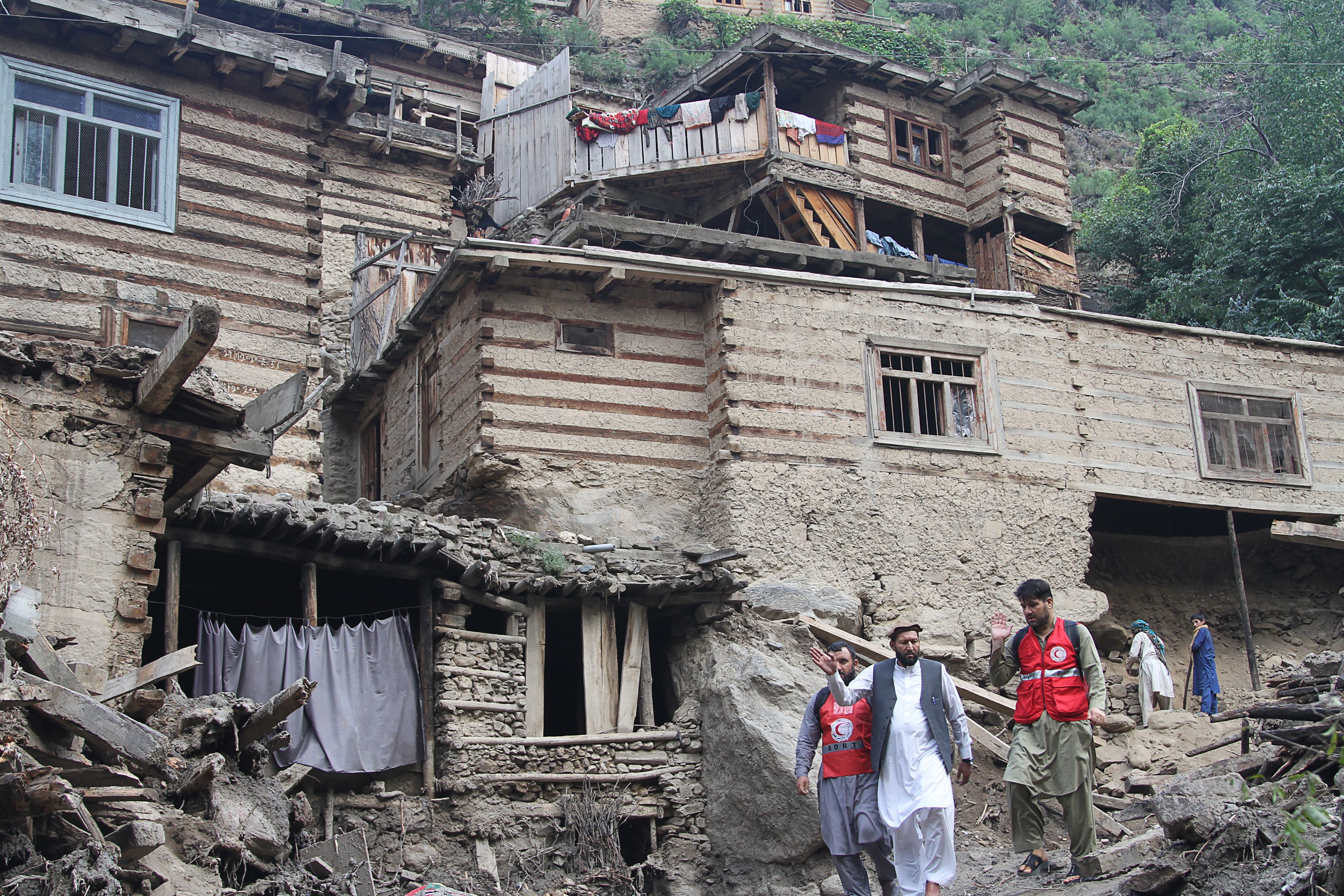 Des personnes face à des habitations endommagées suite aux crues dans la province du Nuristan province,...