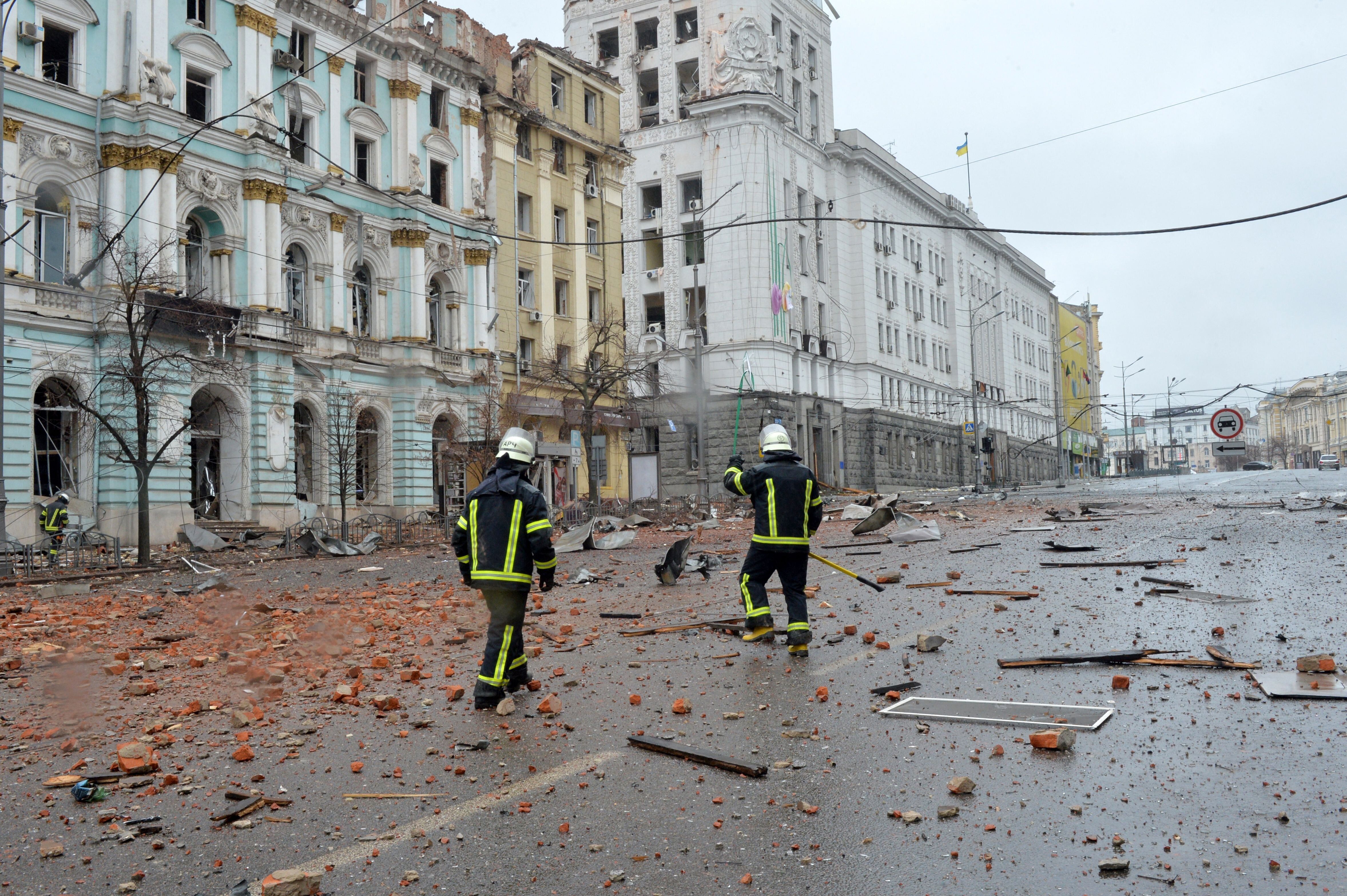 Des pompiers marchant parmi les dégâts après le bombardement par les forces russes...