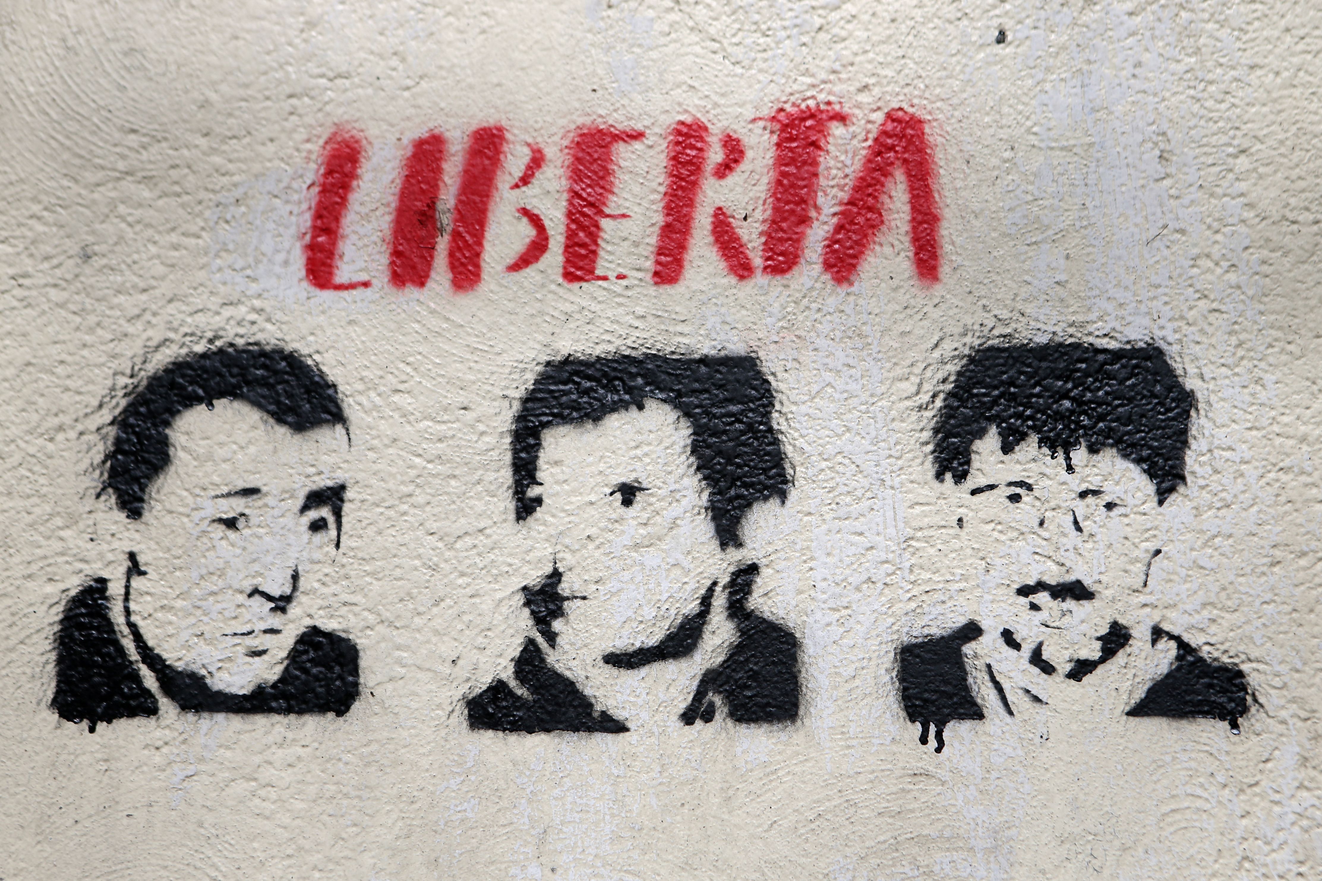 Une photographie prise le 14 mars 2022 à Bastia d'un graffiti à l'éfigie des trois hommes impliqués dans...