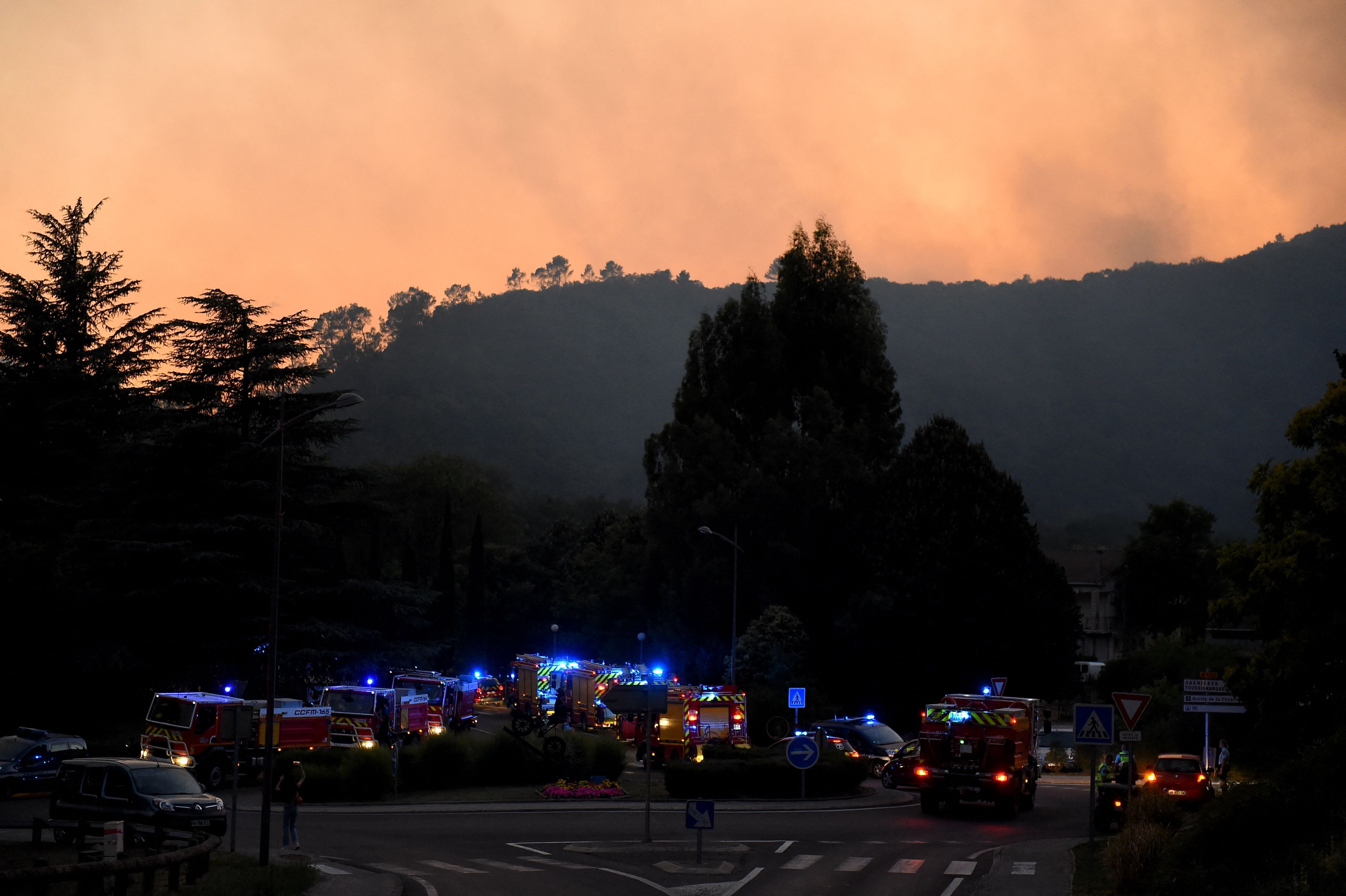 Des véhicules de pompiers rassemblés alors qu'un incendie fait rage sur la colline derrière...